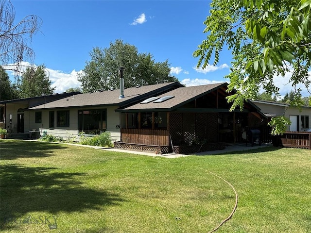 rear view of property with a lawn and a shingled roof