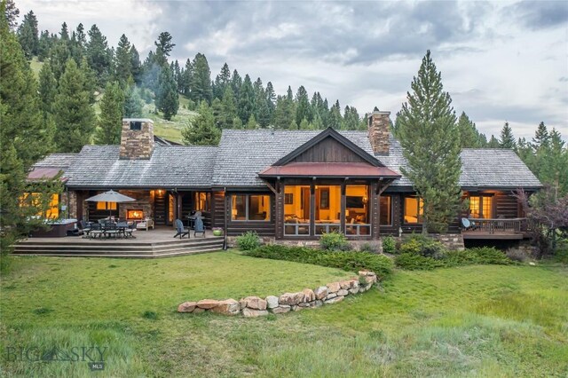 rear view of house featuring a yard and a wooden deck