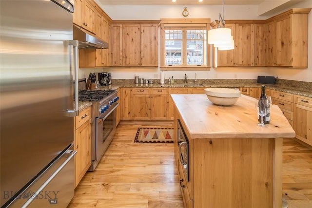 kitchen featuring under cabinet range hood, premium appliances, butcher block countertops, and light wood finished floors