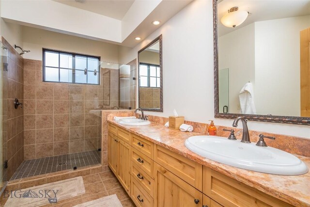 bathroom with a tile shower, dual sinks, tile floors, and large vanity