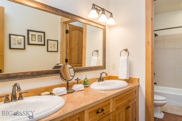 full bathroom featuring double vanity, toilet, and tiled shower / bath