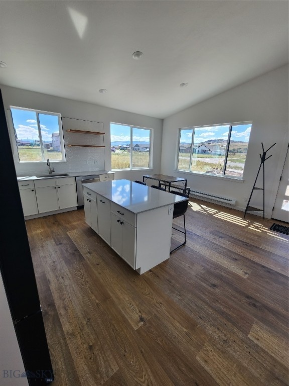 kitchen with a healthy amount of sunlight, a kitchen island, white cabinetry, and dark wood-type flooring