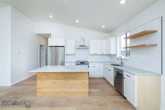 kitchen with wall chimney range hood, lofted ceiling, light hardwood / wood-style flooring, and stainless steel appliances