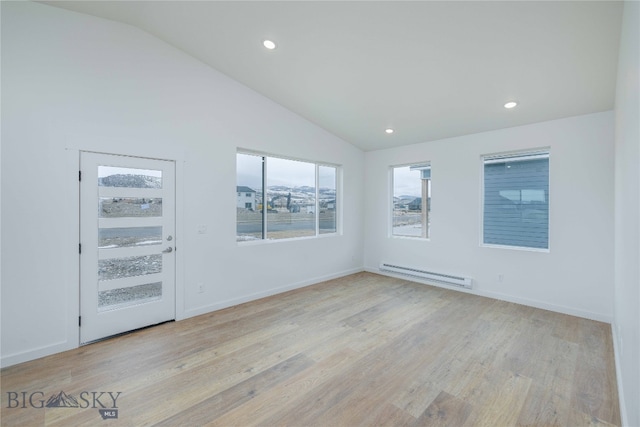 empty room with a baseboard radiator, light wood-type flooring, and vaulted ceiling