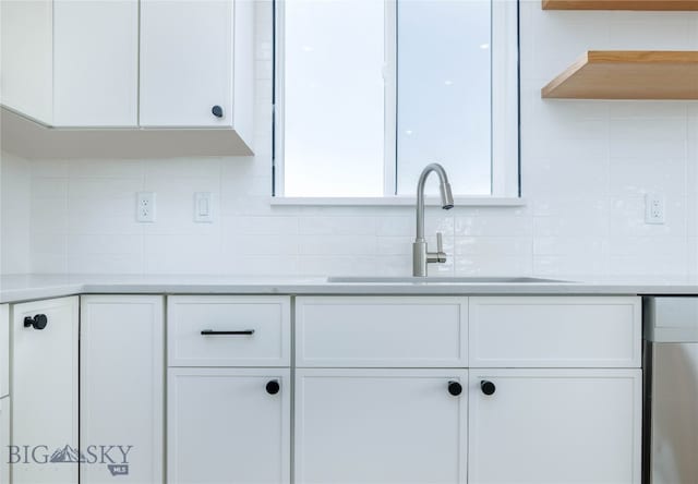 kitchen featuring backsplash, sink, and white cabinetry