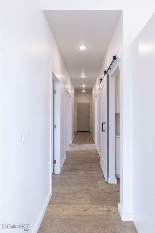 corridor featuring a barn door and hardwood / wood-style flooring