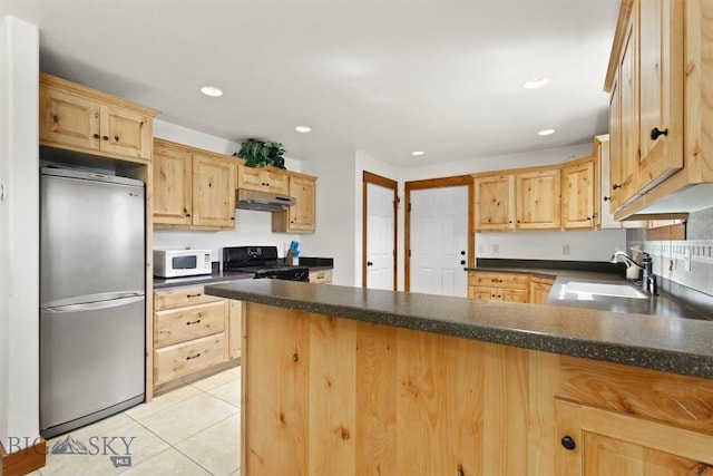 820 Miller Canyon Rd, Three Forks, MT 59752 - kitchen with freestanding refrigerator, white microwave, black range with gas stovetop, light brown cabinets, and a peninsula