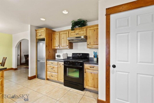 820 Miller Canyon Rd, Three Forks, MT 59752 - kitchen featuring black range with gas stovetop, stainless steel fridge, under cabinet range hood, white microwave, and dark countertops