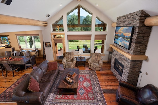 living room with hardwood / wood-style flooring, lofted ceiling, and a stone fireplace