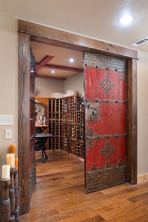 wine area with beamed ceiling and wood-type flooring