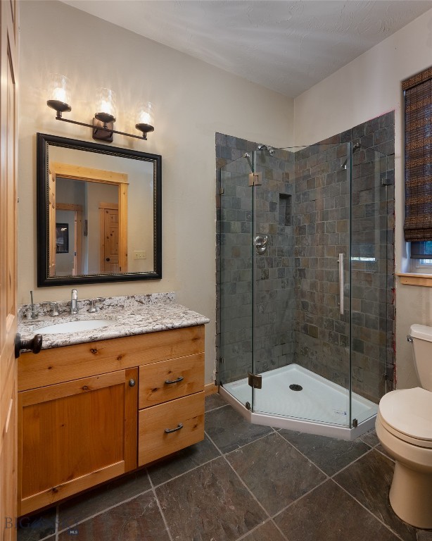 bathroom with vanity, a shower with shower door, toilet, and tile patterned flooring