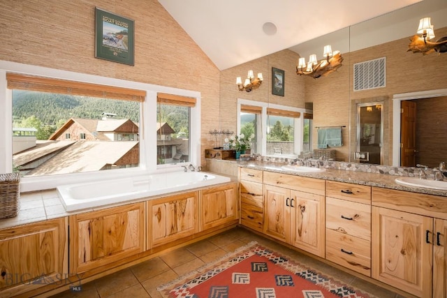 bathroom with tile patterned flooring, high vaulted ceiling, a notable chandelier, a bathtub, and vanity