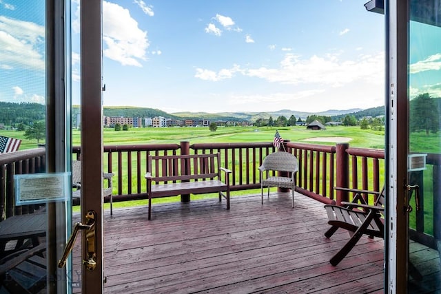 wooden deck with a mountain view and a lawn