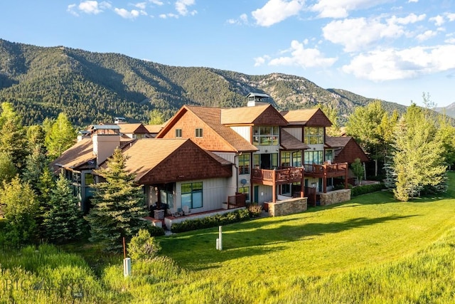 back of property with a lawn and a deck with mountain view