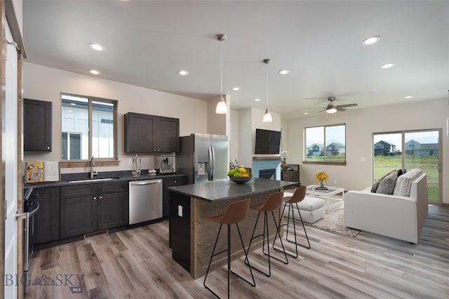 kitchen featuring a kitchen bar, appliances with stainless steel finishes, sink, a center island, and light hardwood / wood-style floors