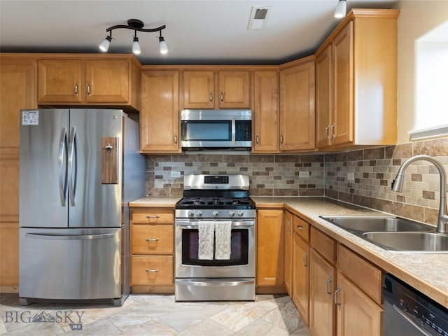 kitchen featuring appliances with stainless steel finishes, backsplash, rail lighting, sink, and light tile floors