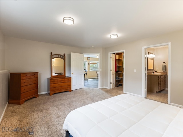 bedroom with a closet, light carpet, sink, connected bathroom, and a walk in closet