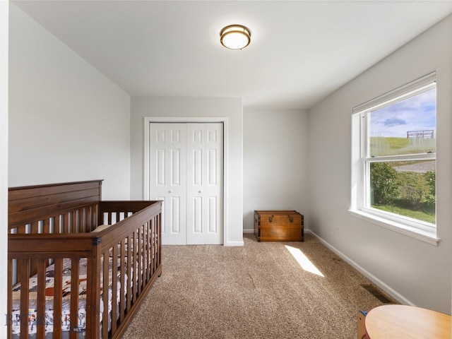 bedroom featuring a nursery area, a closet, and carpet