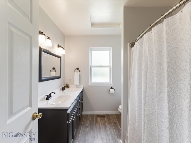 bathroom featuring toilet, hardwood / wood-style flooring, and double sink vanity