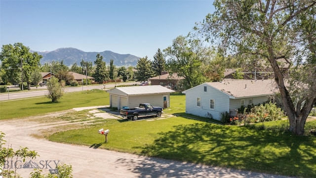 exterior space featuring an outdoor structure, a garage, a mountain view, and a yard