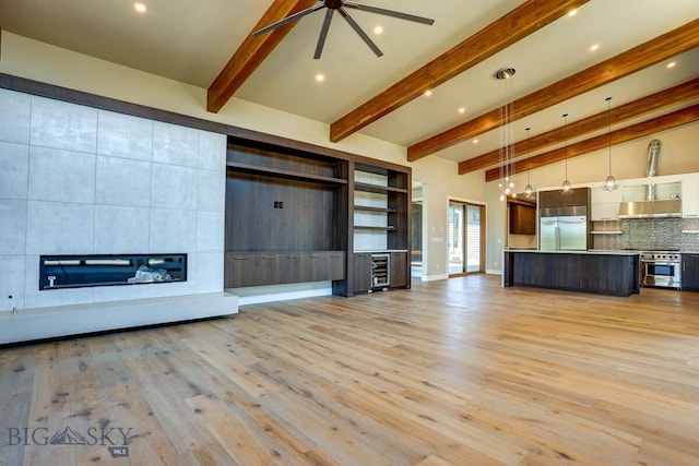 unfurnished living room featuring a tile fireplace, beverage cooler, ceiling fan, light hardwood / wood-style floors, and beam ceiling