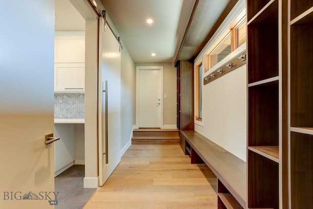 hallway with a barn door and light hardwood / wood-style flooring