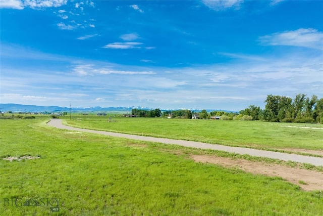 view of property's community featuring a rural view, a mountain view, and a lawn