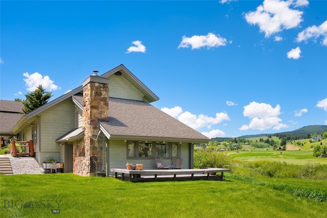 back of property with a mountain view and a yard