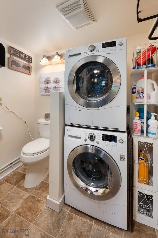 washroom with tile flooring and stacked washer / drying machine