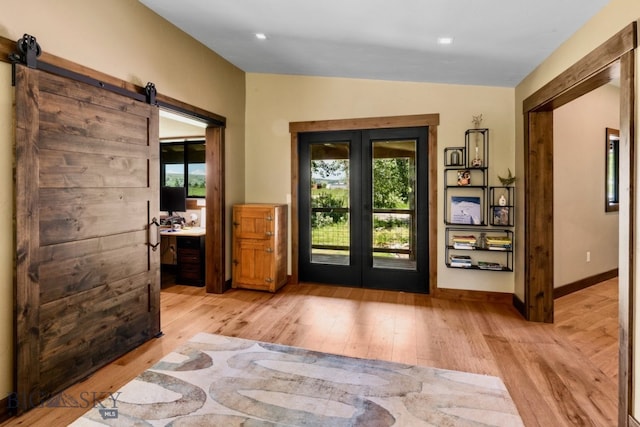 doorway to outside with plenty of natural light, french doors, light hardwood / wood-style flooring, and a barn door