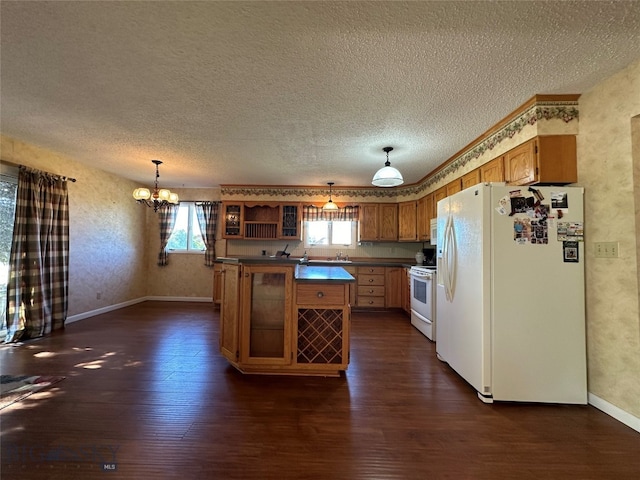 kitchen featuring dark wood-type flooring, hanging light fixtures, white appliances, and an inviting chandelier