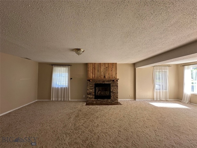 unfurnished living room with carpet flooring, a stone fireplace, and a textured ceiling