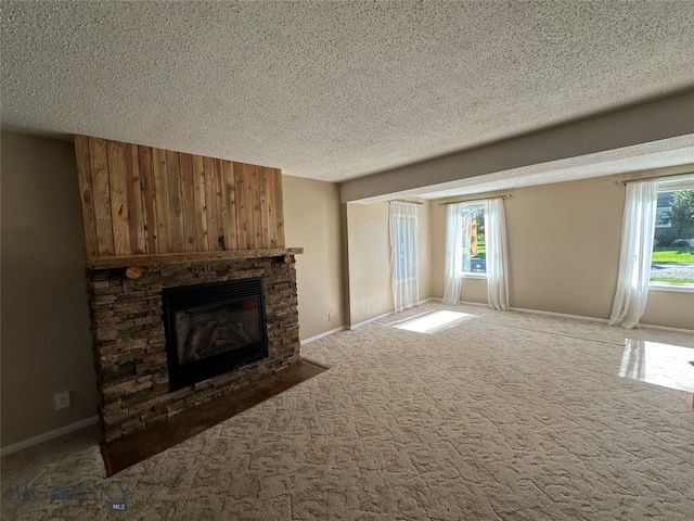 unfurnished living room featuring a stone fireplace, carpet floors, and a textured ceiling