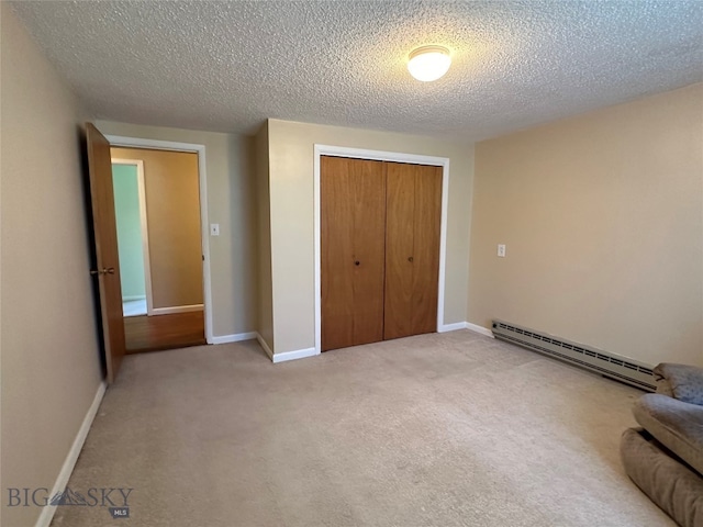 unfurnished bedroom featuring a textured ceiling, carpet floors, baseboard heating, and a closet