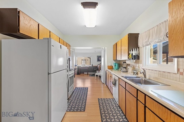 kitchen with light hardwood / wood-style floors, sink, white appliances, and tasteful backsplash