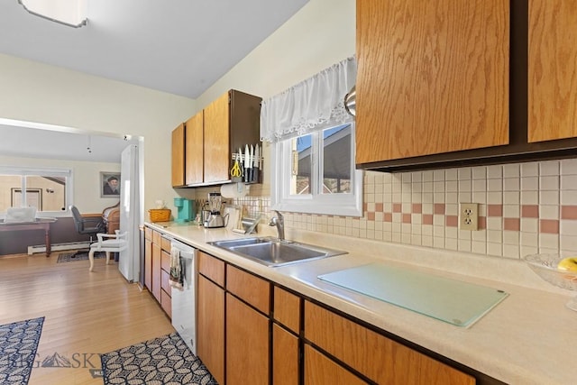 kitchen featuring light hardwood / wood-style flooring, baseboard heating, backsplash, white dishwasher, and sink