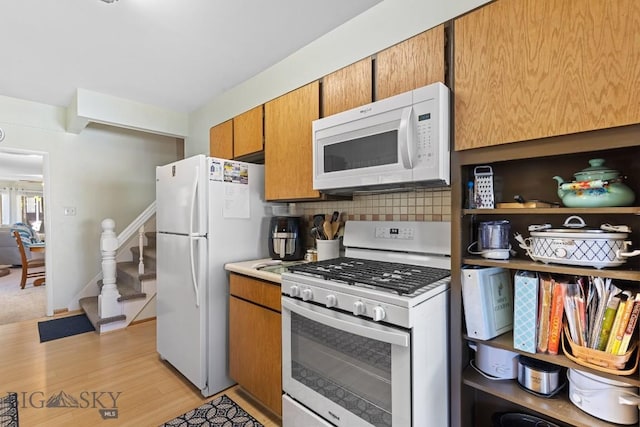 kitchen featuring tasteful backsplash, white appliances, and light hardwood / wood-style flooring