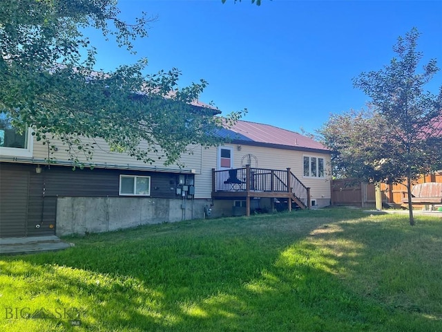 rear view of house with a wooden deck and a lawn