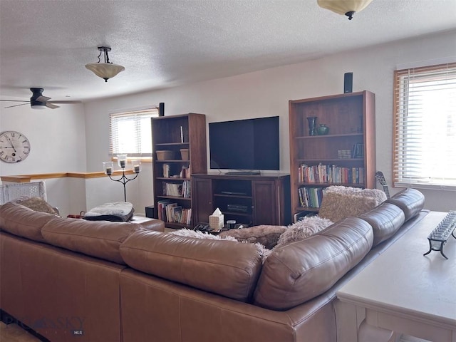 living room with a textured ceiling and ceiling fan