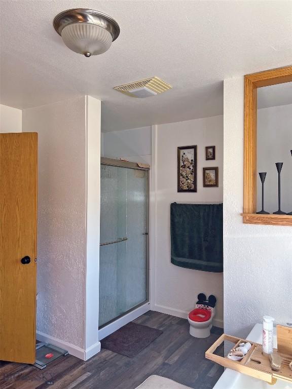 bathroom with hardwood / wood-style flooring, a textured ceiling, and a shower with door