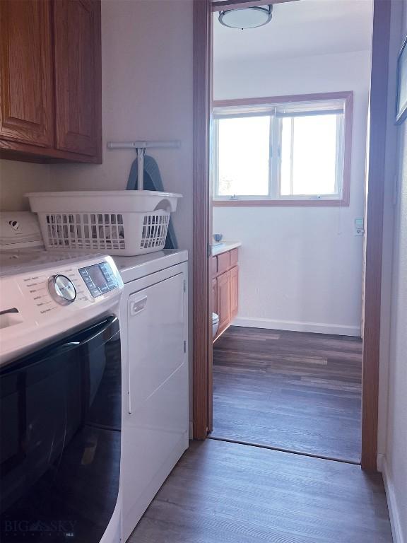 clothes washing area featuring separate washer and dryer, cabinets, and wood-type flooring