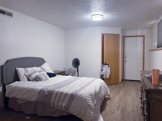 bedroom featuring a textured ceiling and light hardwood / wood-style flooring