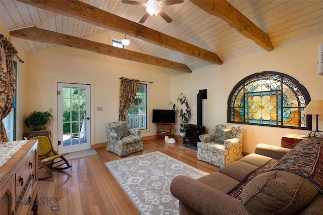 living room featuring ceiling fan, vaulted ceiling with beams, wood ceiling, a wood stove, and light hardwood / wood-style floors