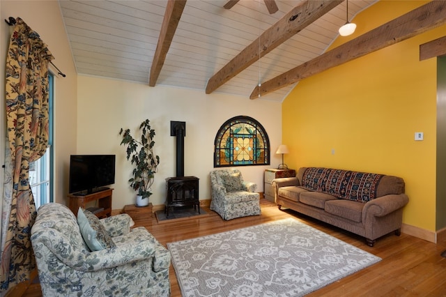 living room featuring lofted ceiling with beams, ceiling fan, wood-type flooring, wood ceiling, and a wood stove