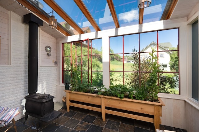 sunroom / solarium featuring a wood stove, lofted ceiling with skylight, and a wealth of natural light