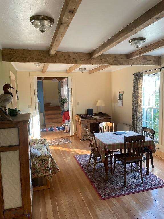 dining room with beamed ceiling and light hardwood / wood-style floors