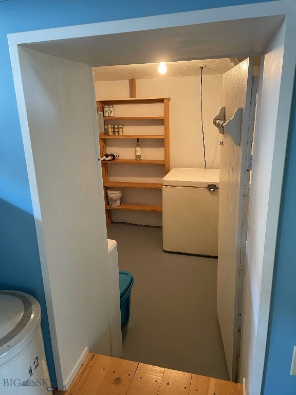 basement featuring hardwood / wood-style floors and refrigerator