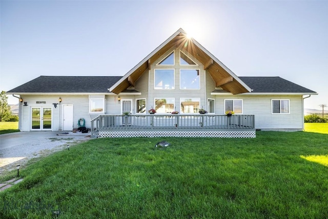 rear view of property with a lawn, a deck, and french doors