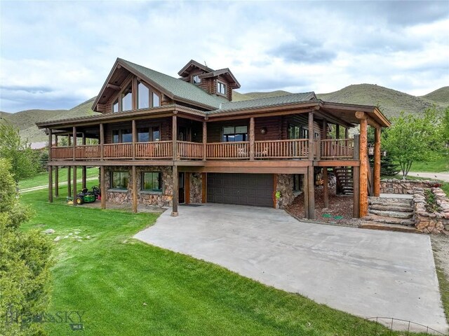 cabin featuring a garage, a mountain view, and a front lawn