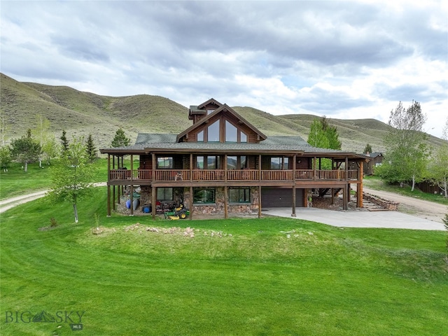 back of house with a lawn and a deck with mountain view